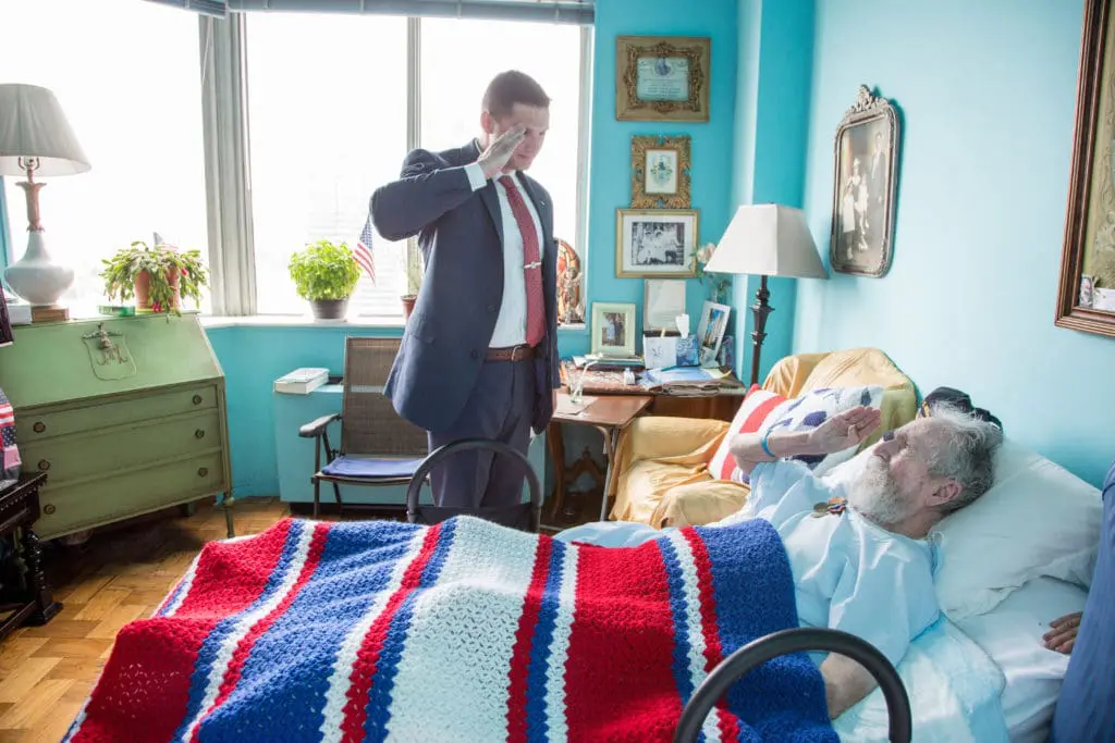 A VNS Health team member salutes a hospice Veteran patient, honoring their service during a moment of care.