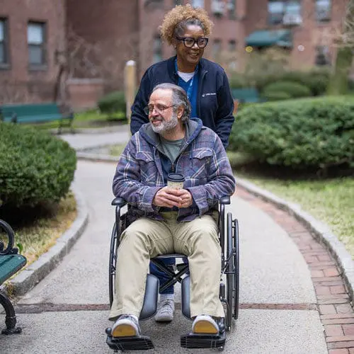 VNS Health home health aide walking with a patient outdoors