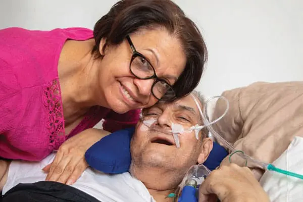 Daughter of a VNS Health Hospice Care patient smiling next to her elderly father.