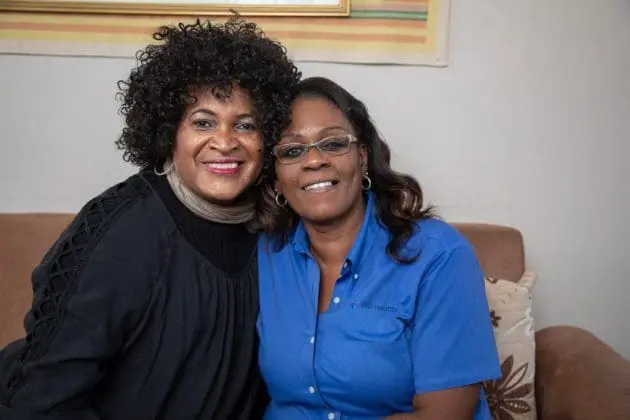 A patient of the VNS Health Gender Affirmation Program and her nurse sit together on a couch.