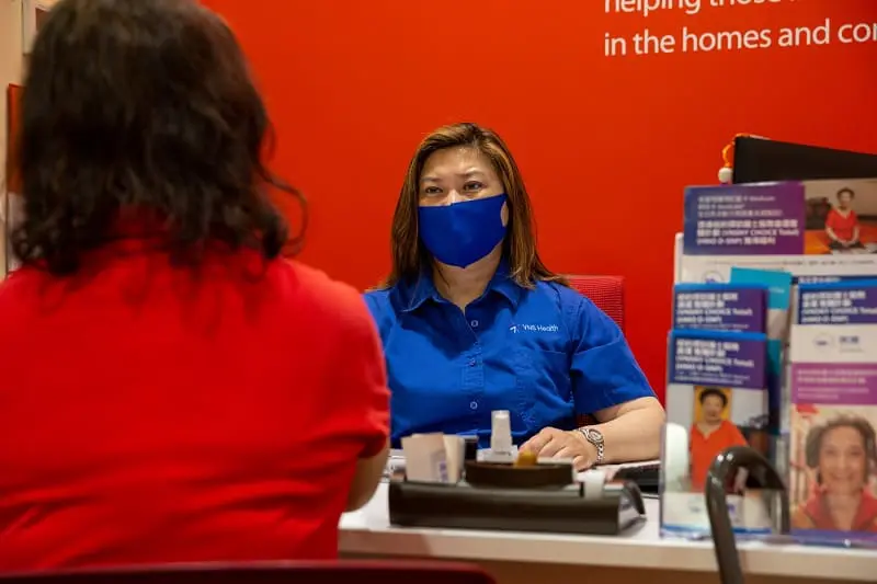 A VNS Health team member helping community members at the Chinatown Community Center front desk.