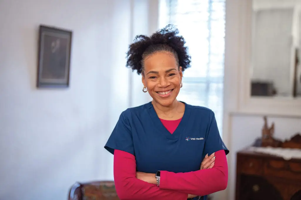 A VNS Health home health aide wearing a magenta shirt.