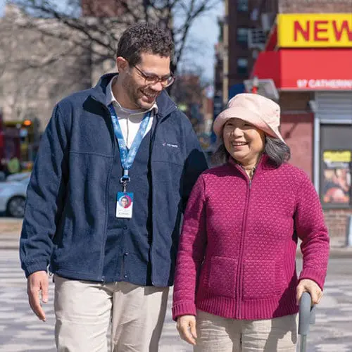 A VNS Health physical therapist helping a patient walk outside.