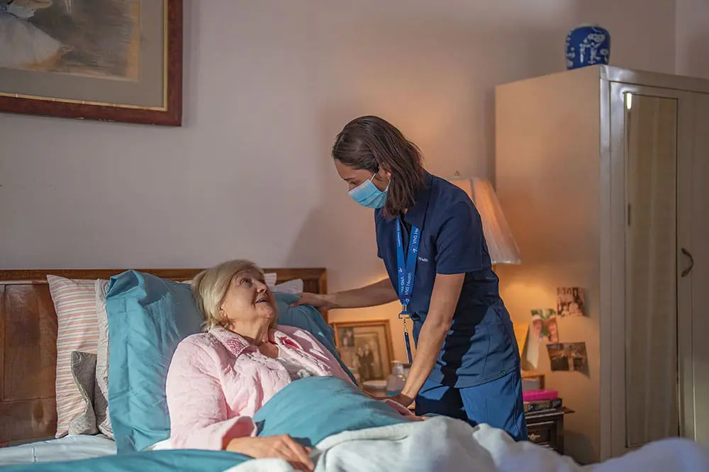 A VNS Health nurse talking to a hospice patient who is bed-bound.