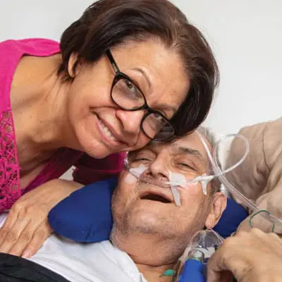 Daughter of a VNS Health Hospice Care patient smiling next to her elderly father.