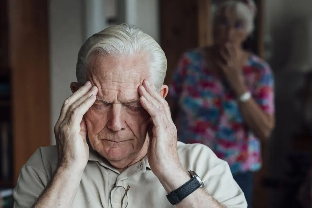 An elderly man suffering with pain from a headache.
