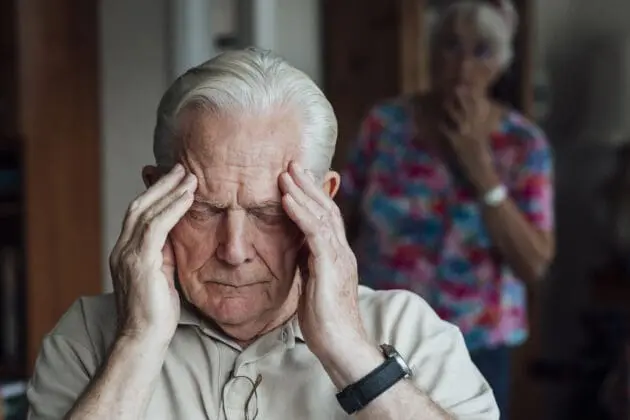 An elderly man suffering with pain from a headache.
