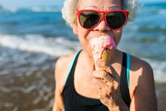 An elderly woman eating ice cream.