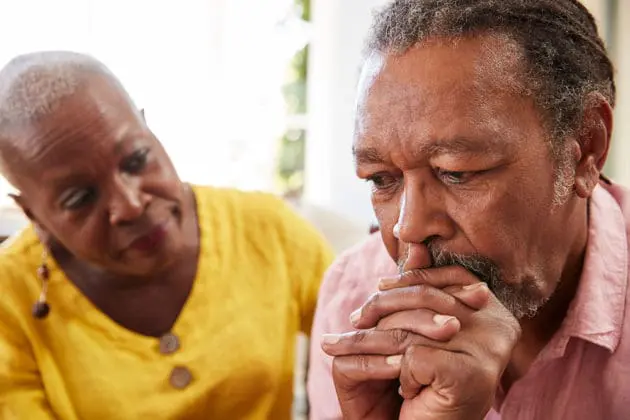 A caregiver looking at frowning man.