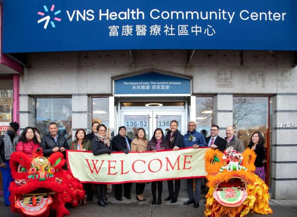 VNS Health team members standing in front of the Flushing Community Center holding a welcome banner.