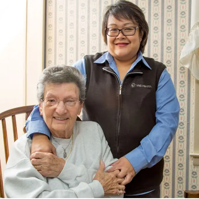A VNS Health home health aide standing behind her patient.