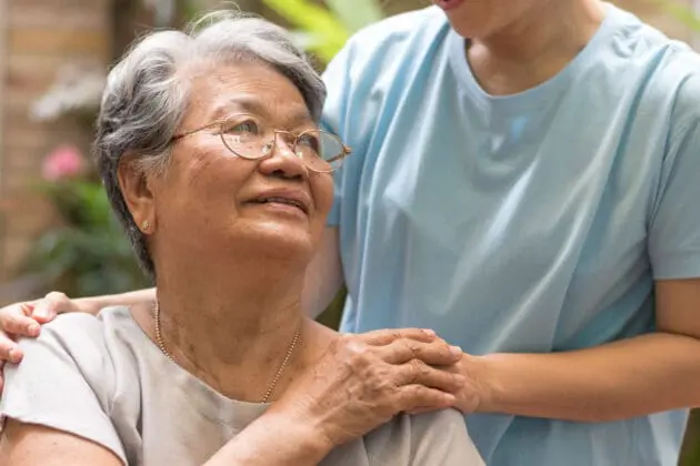 A caregiver and patient holding hands.