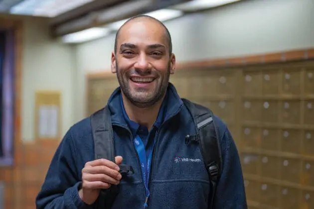 home health aide standing in a hallway smiling.