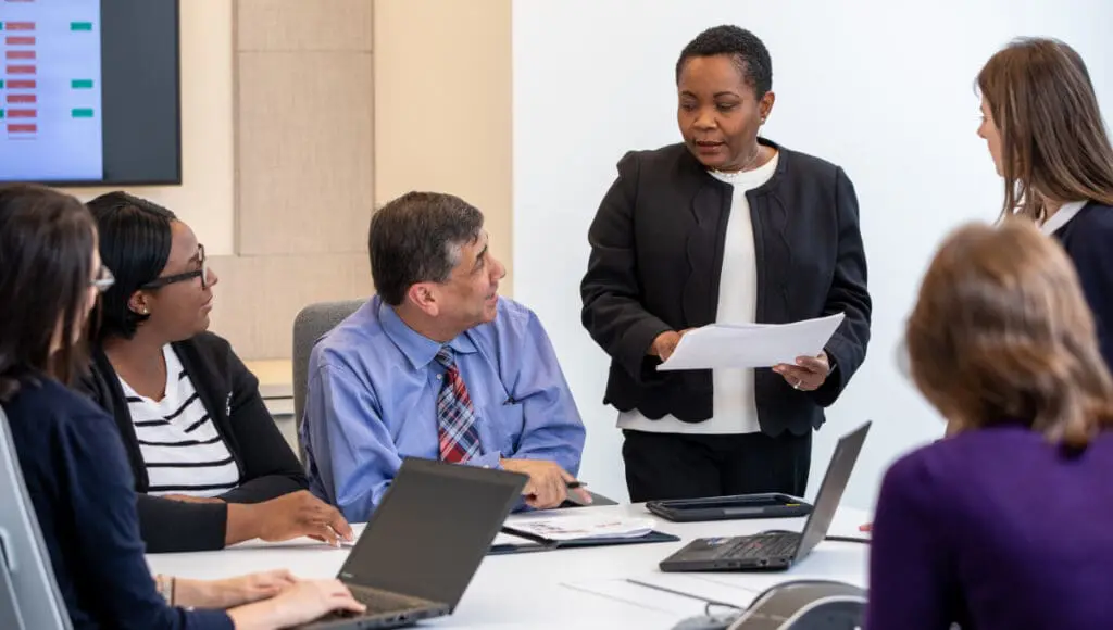 Six VNS Health employees gathered in a meeting to discuss Hospice performance.