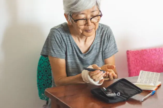 A senior women checking her blood sugar with a glucometer at home.