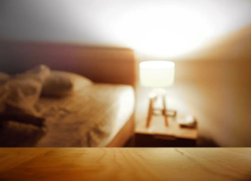 A bedside table with a lamp casting a glow around the room.