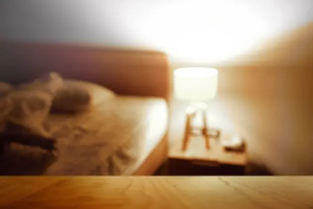 A bedside table with a lamp casting a glow around the room.
