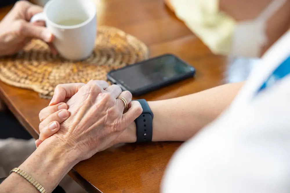 Hospice patient holding hands with a loved one.