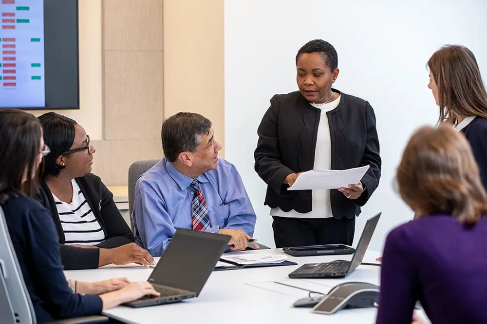 Six VNS Health employees gathered in a meeting to discuss Hospice performance.