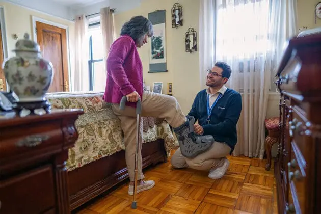 A VNS Health Physical Therapist helping his patient put on a walking boot.