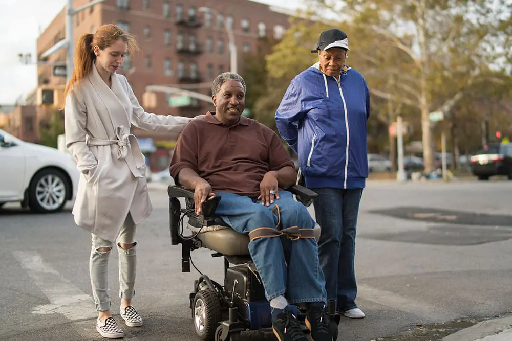 Two family members walking next to a VNS Health Veteran patient.