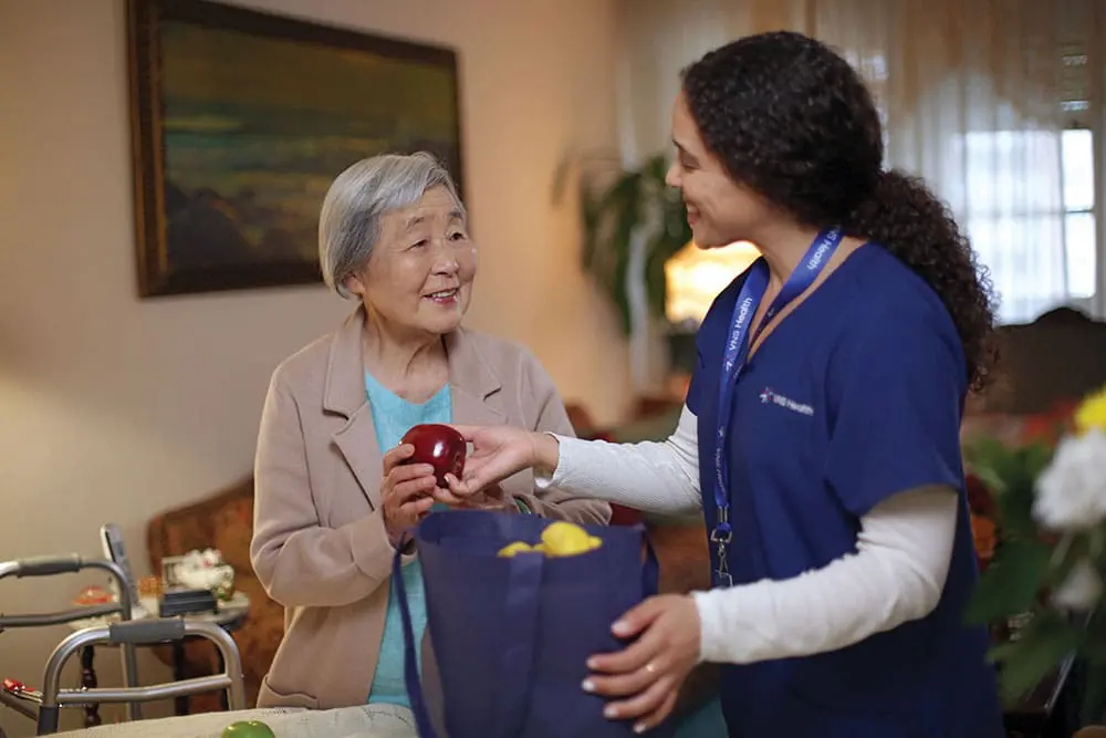A VNS Health home health aide helping her patient with groceries.