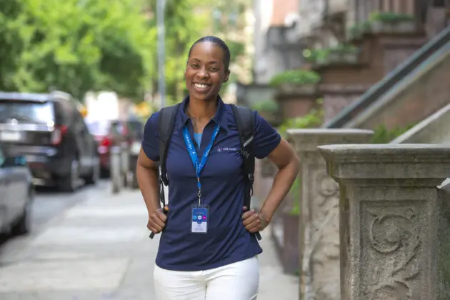 A VNS Health team member posing on the sidewalk and smiling.