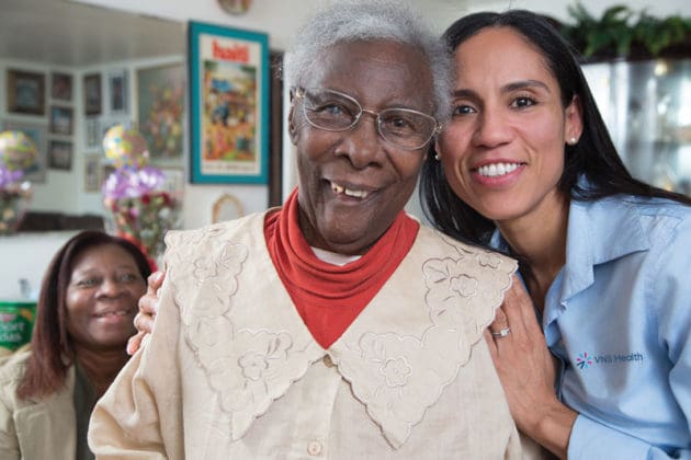 A VNS Health home health aide smiling next to her patient.
