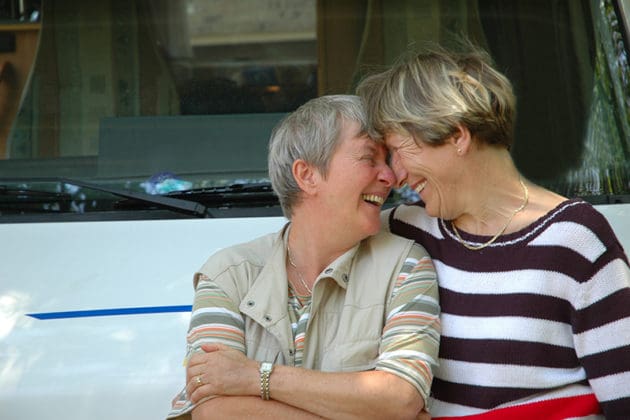 Two older adult women laughing and hugging.