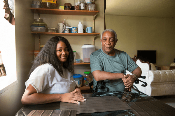 Home health aide sitting with George, a member of health plans from VNS Health.