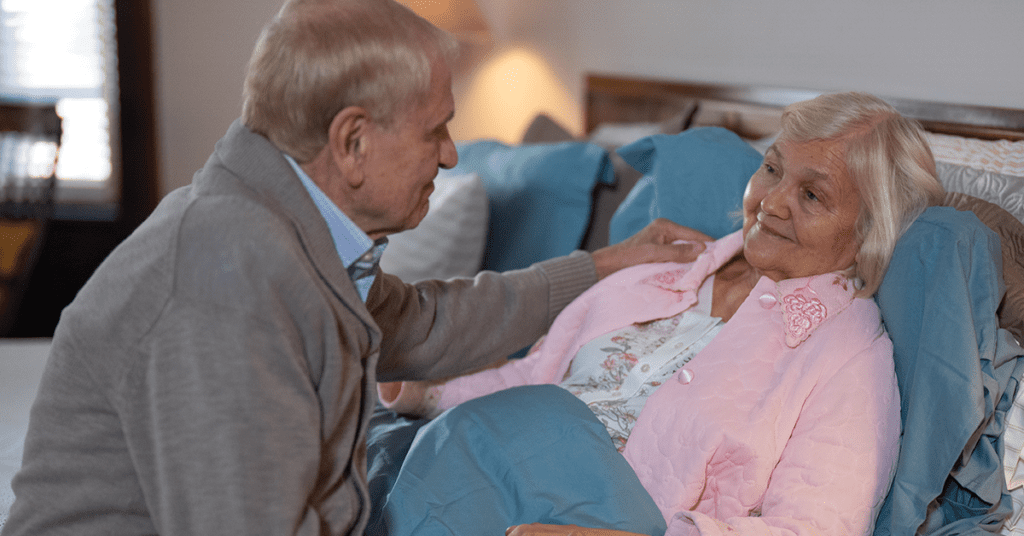 Photo of elderly man caring for his bedridden wife