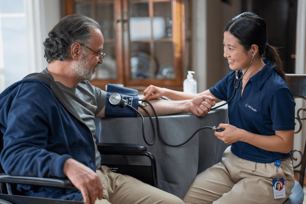 Photo of VNS Health nurse taking a patient's blood pressure at kitchen table