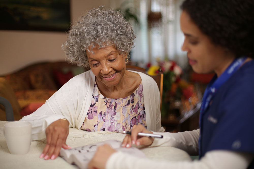elderly woman reading book with care team member