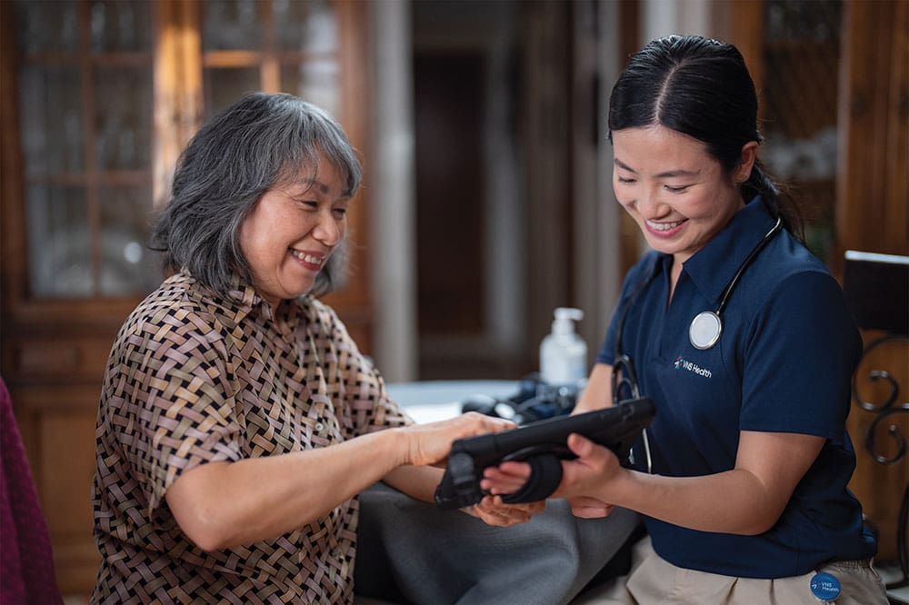 elderly asian woman looking at ipad with care team member