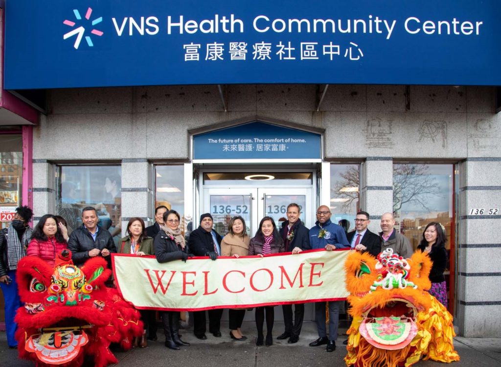 VNS Health team members in front of Flushing community center holding welcome banner