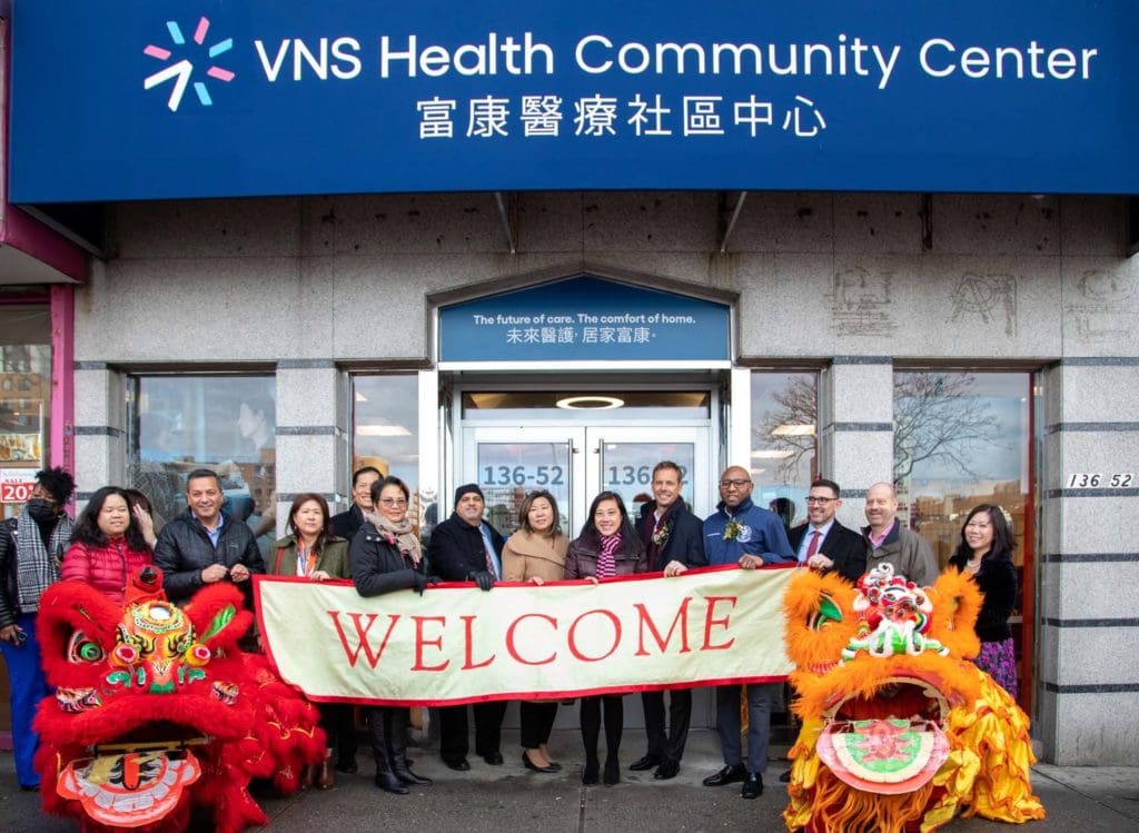 VNS Health team members in front of Flushing community center holding welcome banner