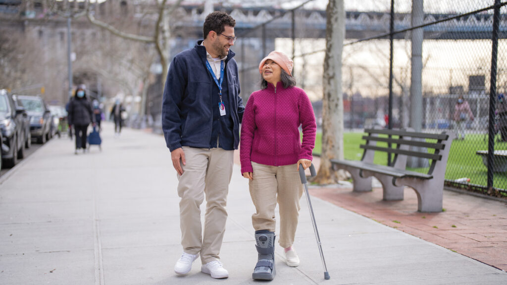 vns health male team member walking with elderly woman with cane in park
