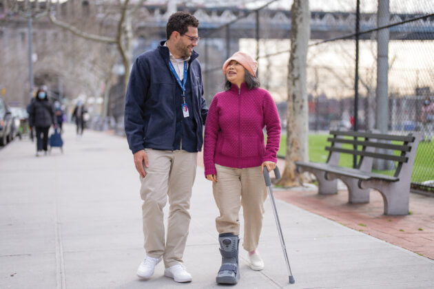 vns health male team member walking with elderly woman with cane in park