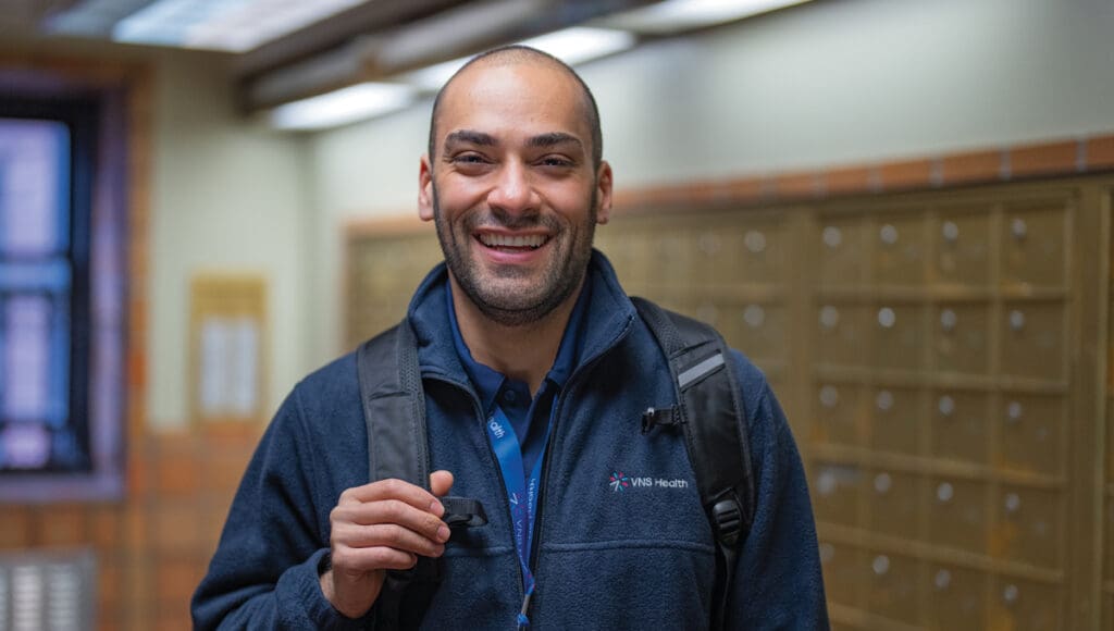 home health aide standing in a hallway smiling.