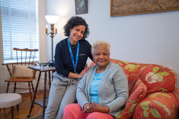 A VNS Health team member and patient sitting on a pink sofa.